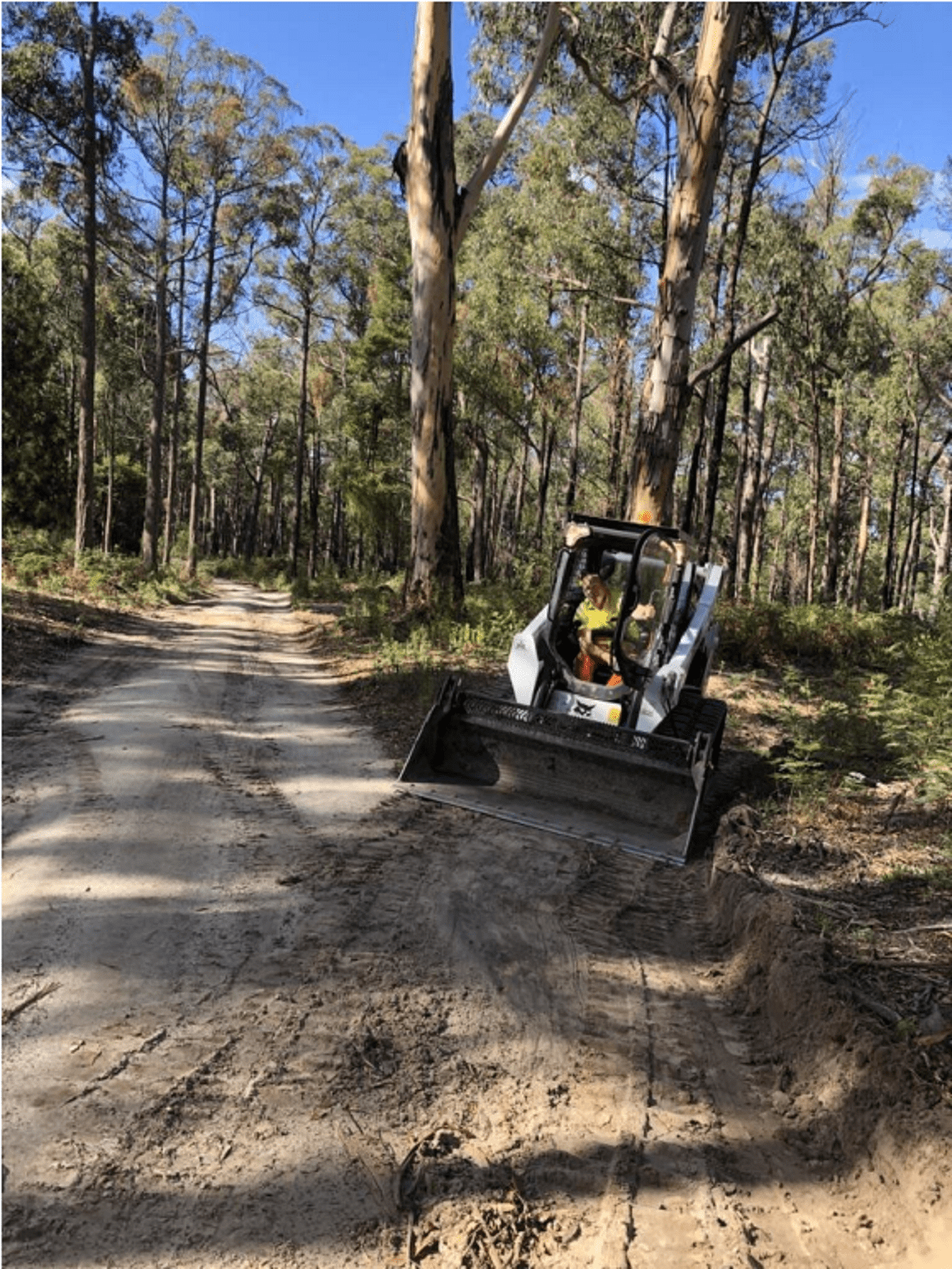 Image shows road repairs by a Parks Victoria staff member in a digger
