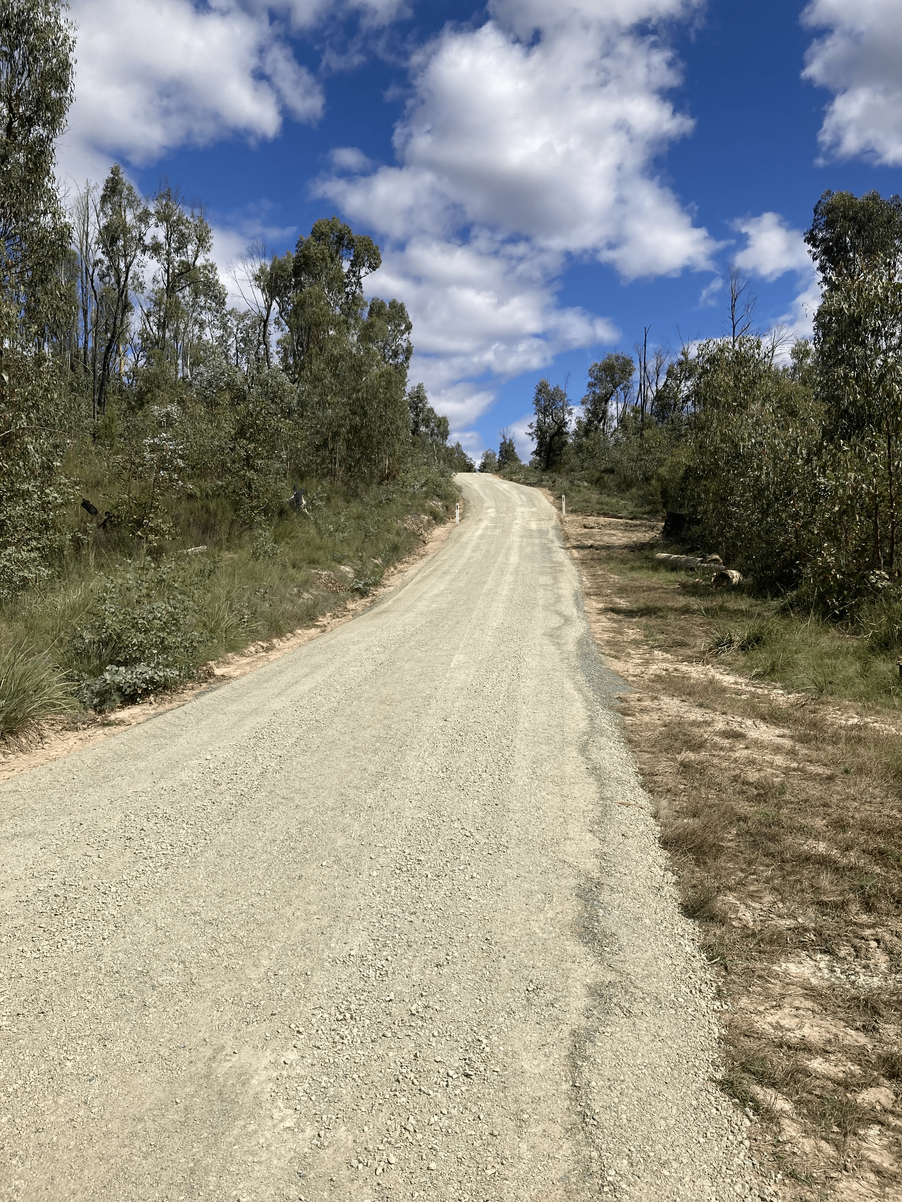An unpaved road heading up a hill with a smooth, new surface
