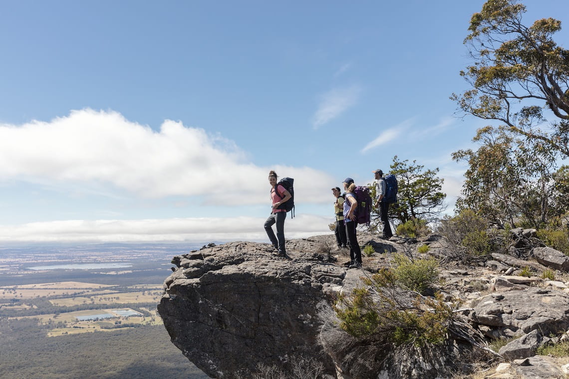 Group of walkers standing on a rock looking over to views in the distance