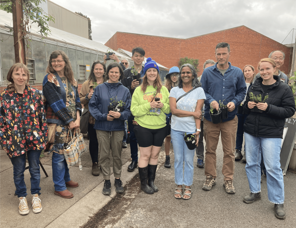 A group of volunteers holding potted cuttings and smiling 