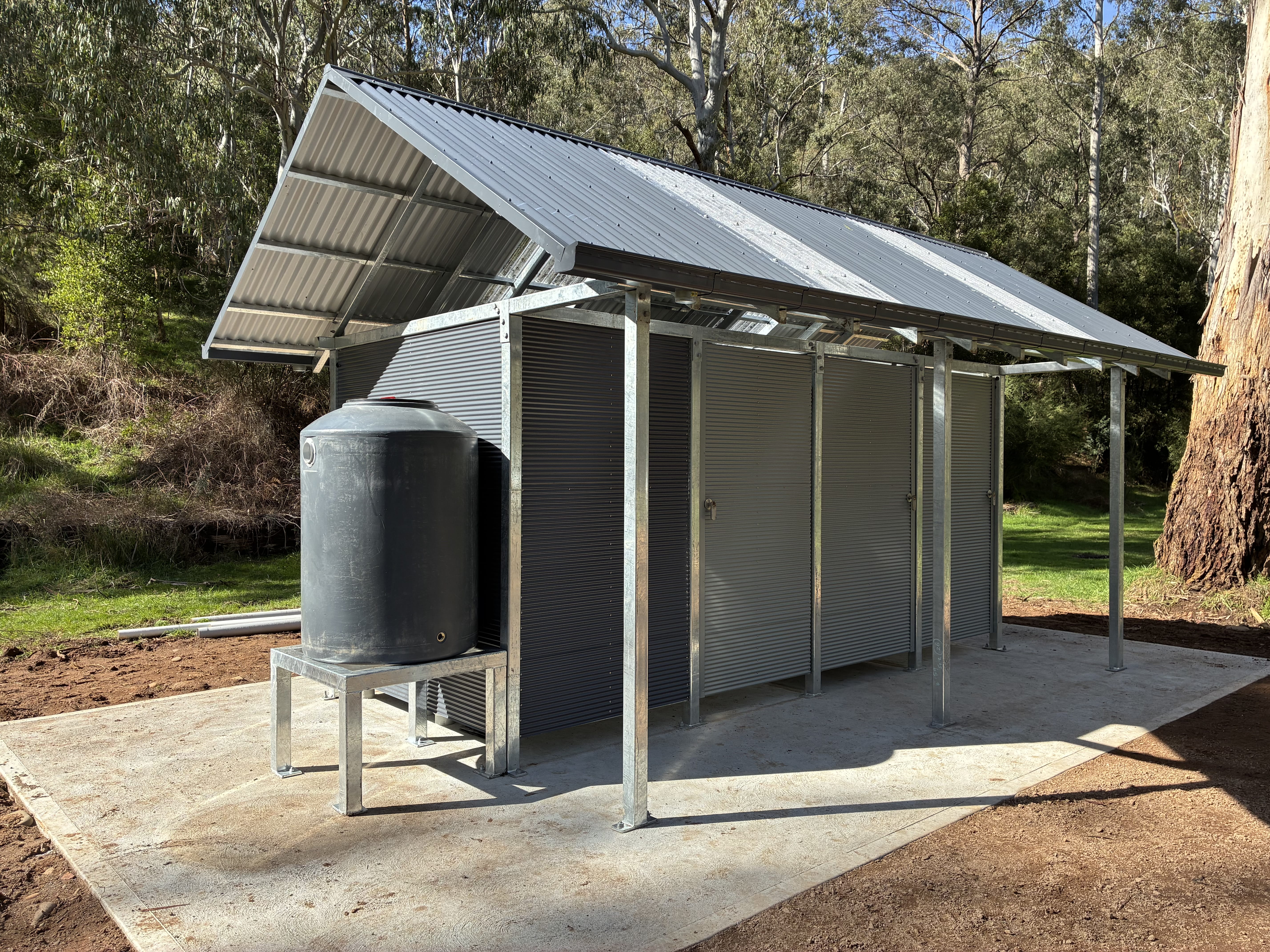 A 3 cubicle toilet block with a watertank beside it