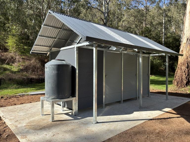 A 3 cubicle toilet block with a watertank beside it