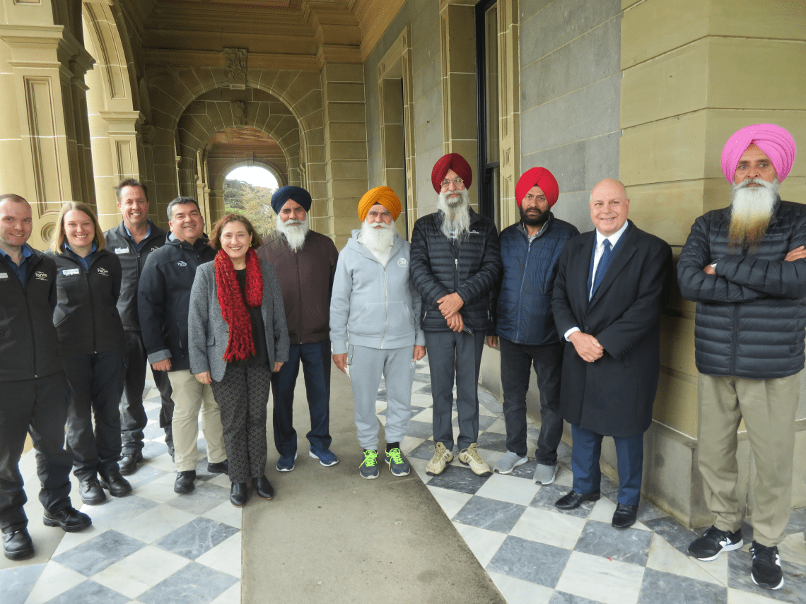Minister D'Ambrosio, MP Tim Pallas, Parks Victoria staff and Sikh and Karen communities smiling outside Werribee Park Mansion