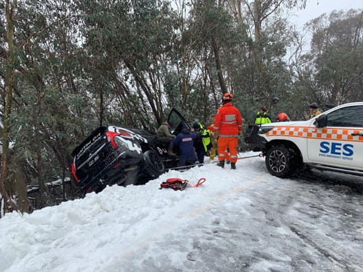 Black car being pulled out of a snowbank by an SES vehicle