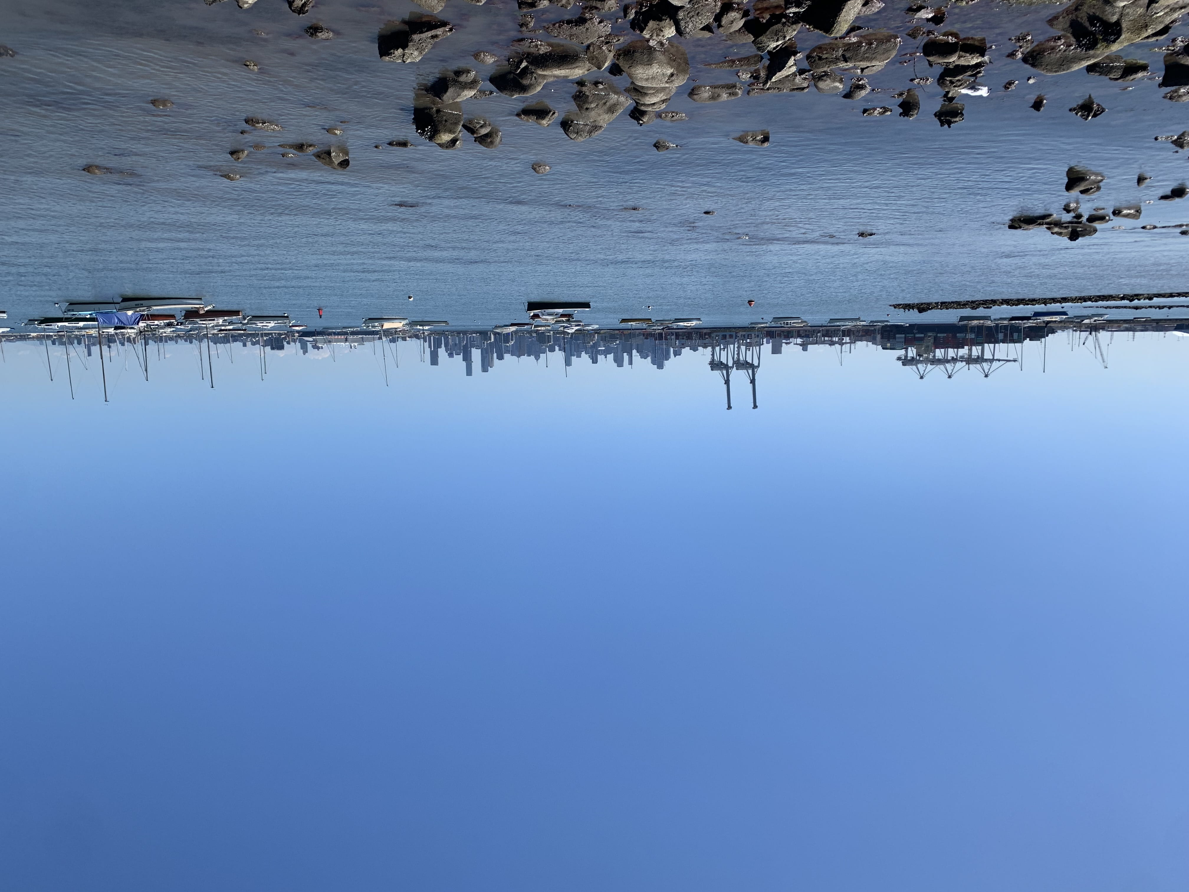 An expanse of water with several boats, in the distance, the cranes of a dockyard and the towers of Melbourne CBD