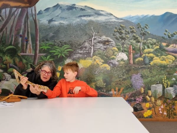 Woman holding and admiring boomerang with young boy