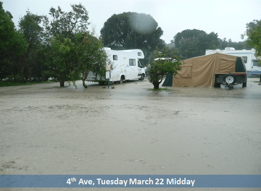 A flooded campground with a campervan and tent surrounded by water.
