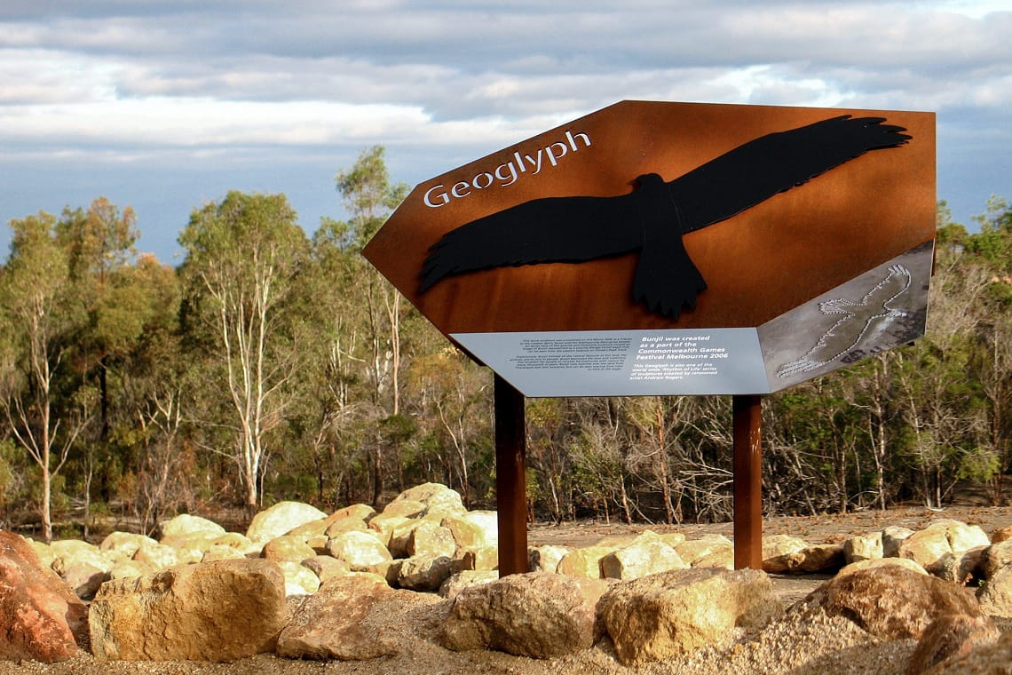 A large sign with an eagle on it and the word Geoglyph. There are rocks under the sign.