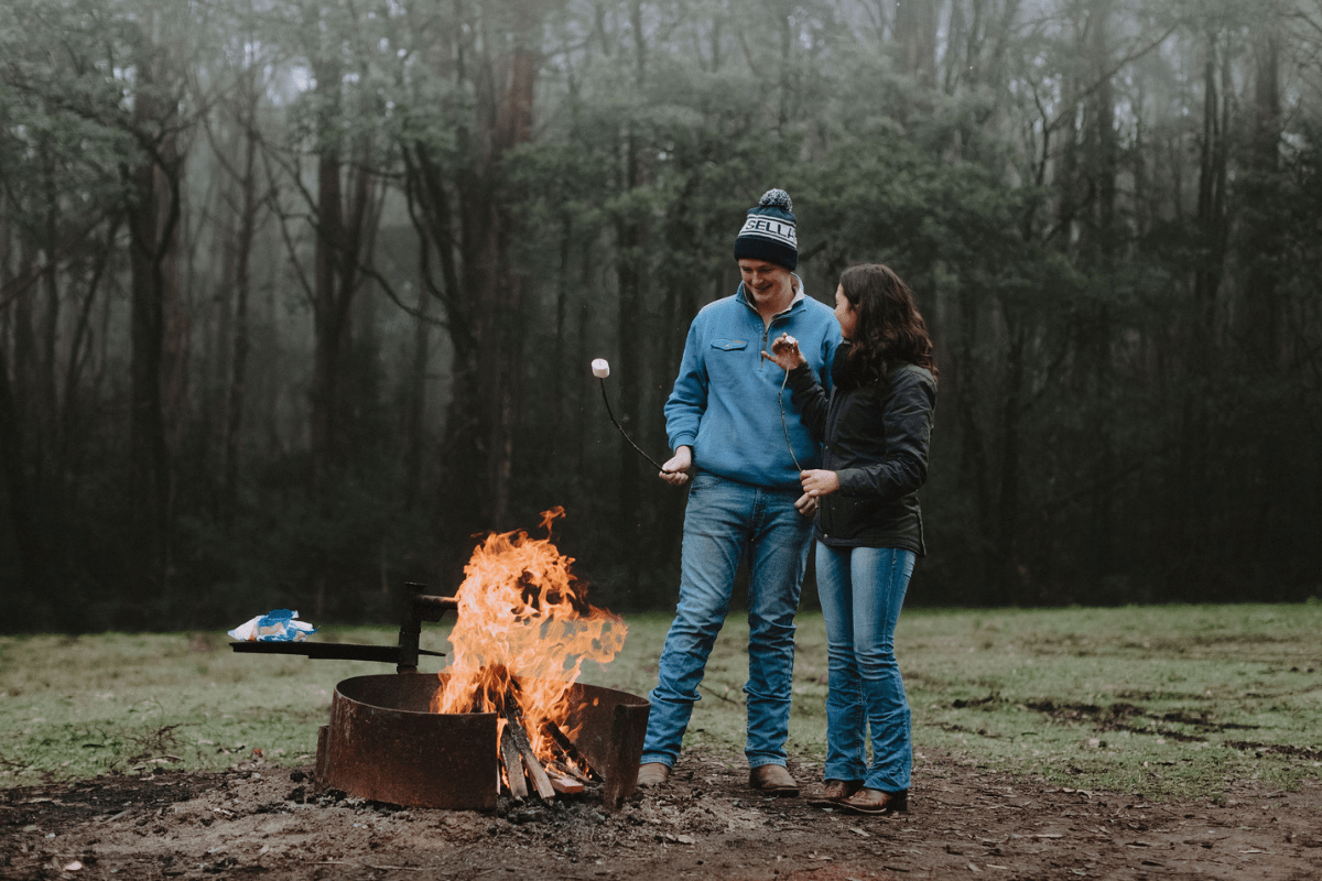 Two people standing around campfire at Days Picnic Area in Macedon Regional Park.