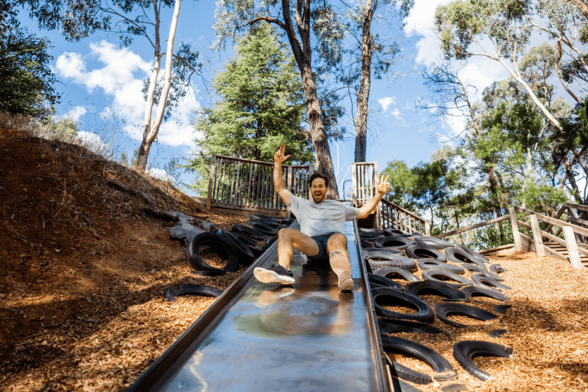 Male adult sliding down wide outdoor slide at Vaughan Springs.