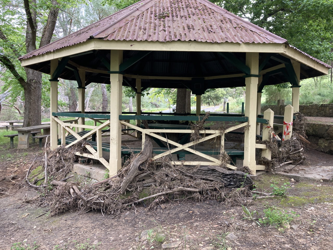An octagonal band stand covered with branches and mud