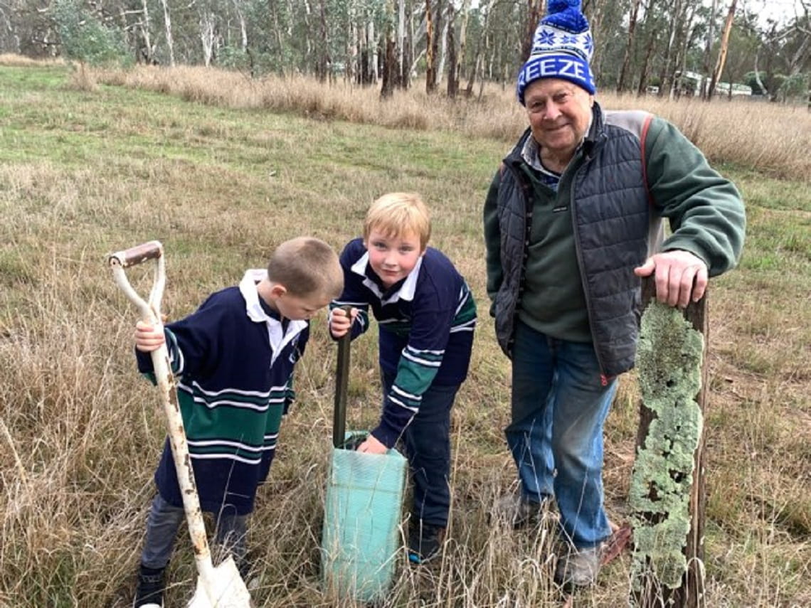 Person gardening with two young children