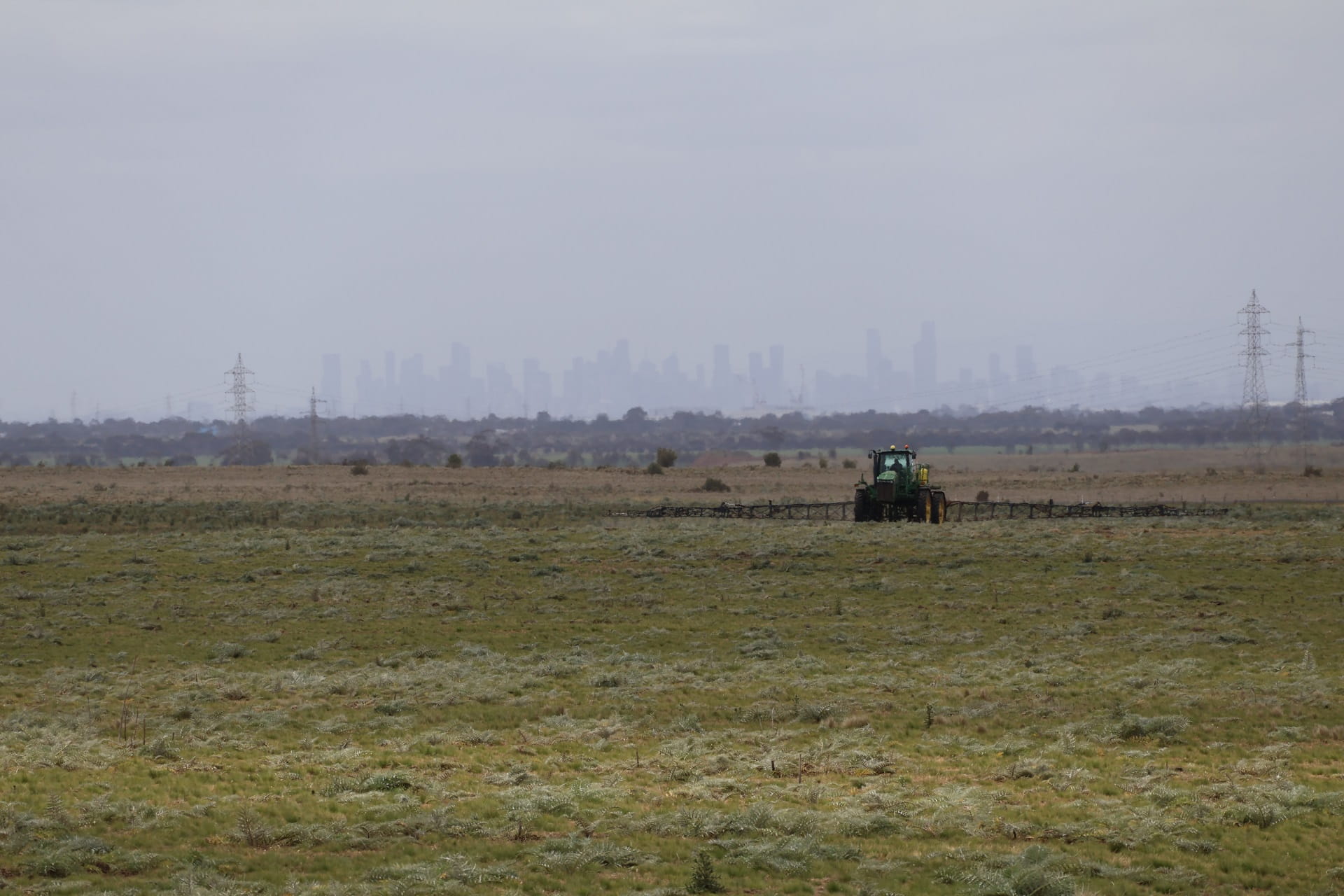trator spraying weeds with city in the background