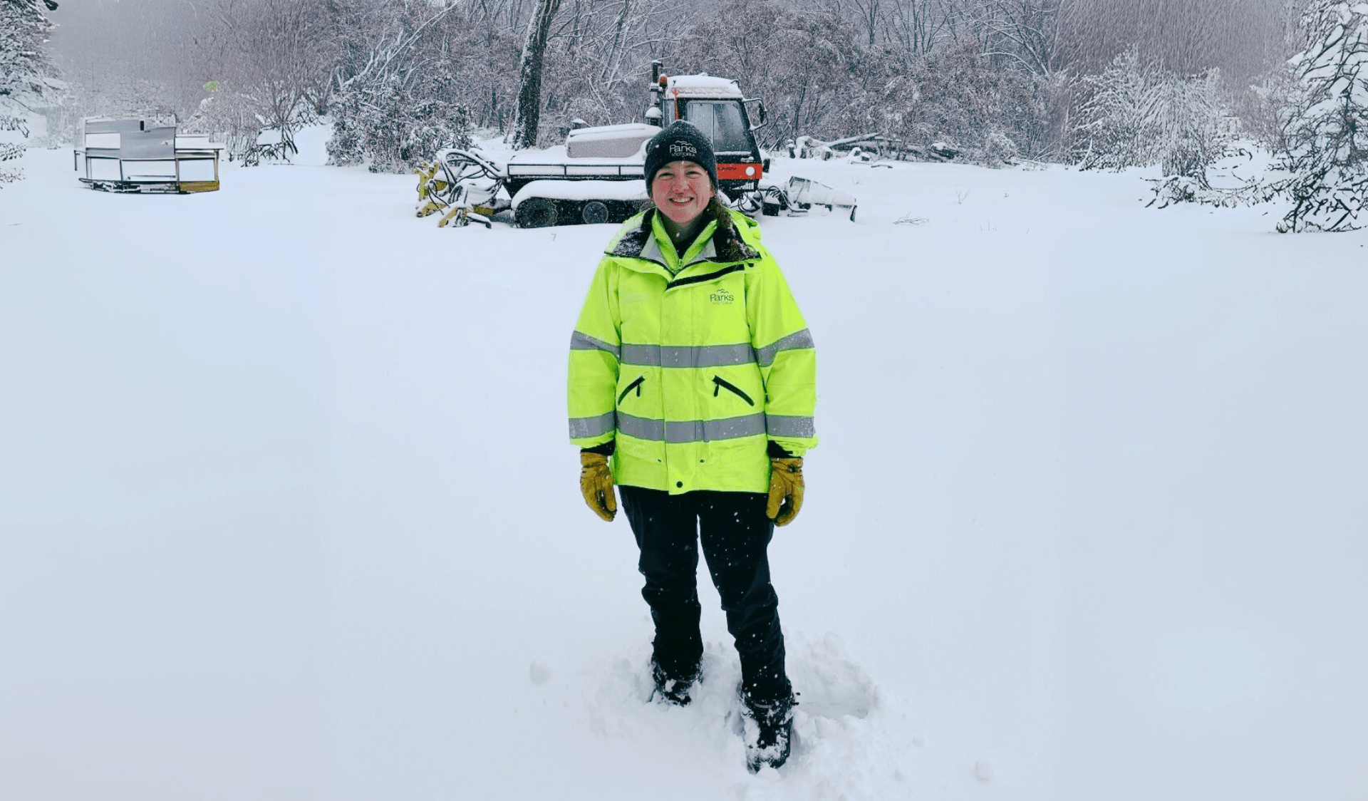 Parks Victoria employee smiling against snow covered hills in Mount Buffalo