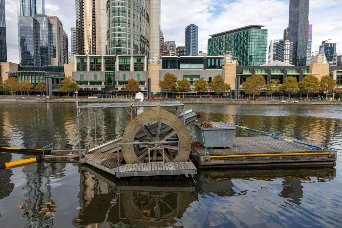A barge with a water wheel and skip filling with rubbish in front of the Crown Casino in central Melbourne