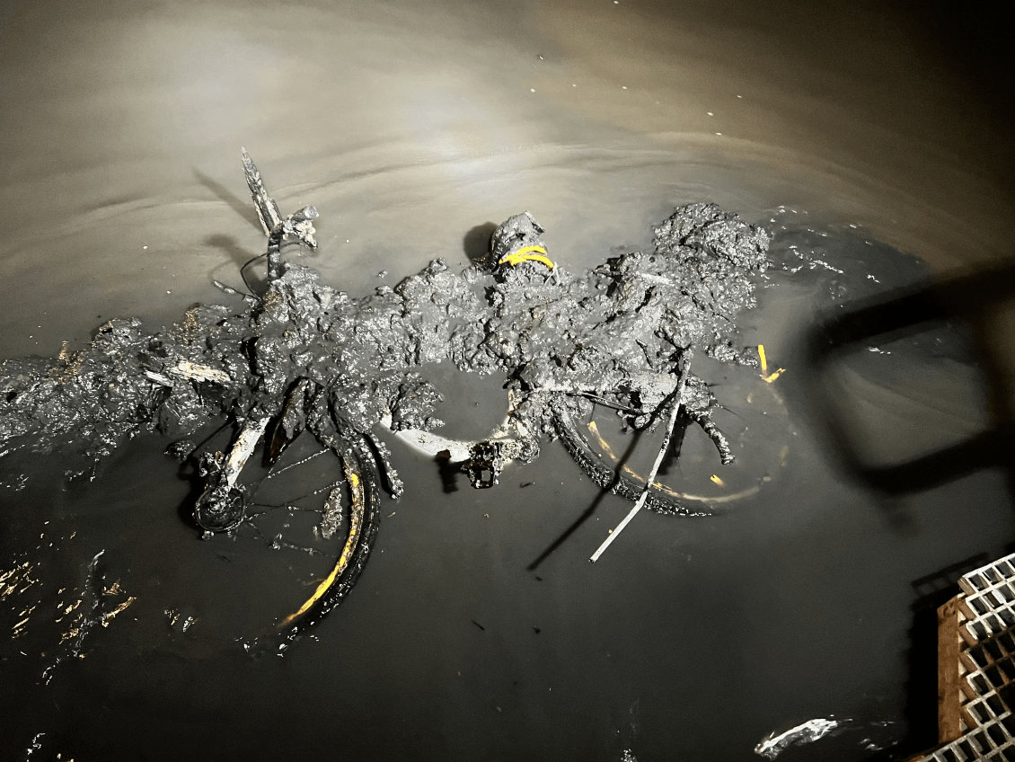 A bike, covered in mud, is lifted from the Yarra River.