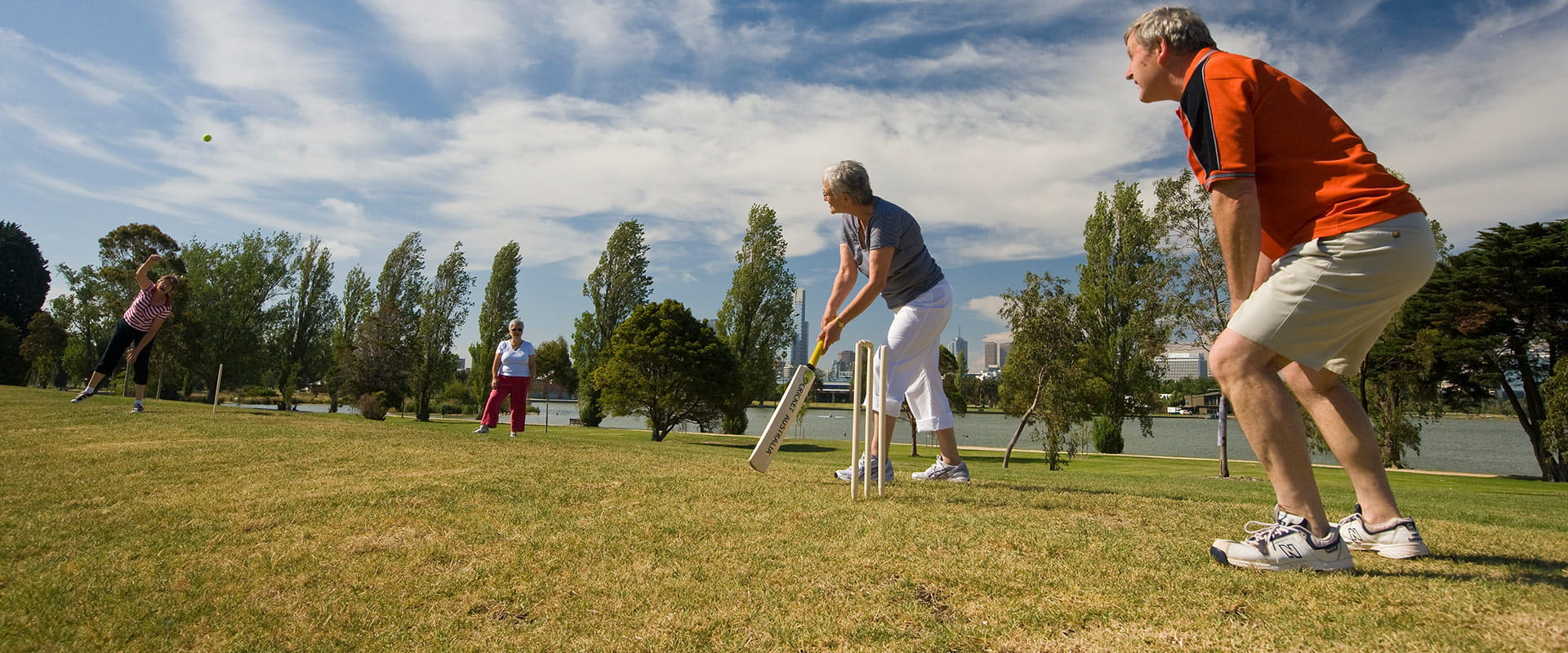 A group of community members play a game of cricket near the lake.