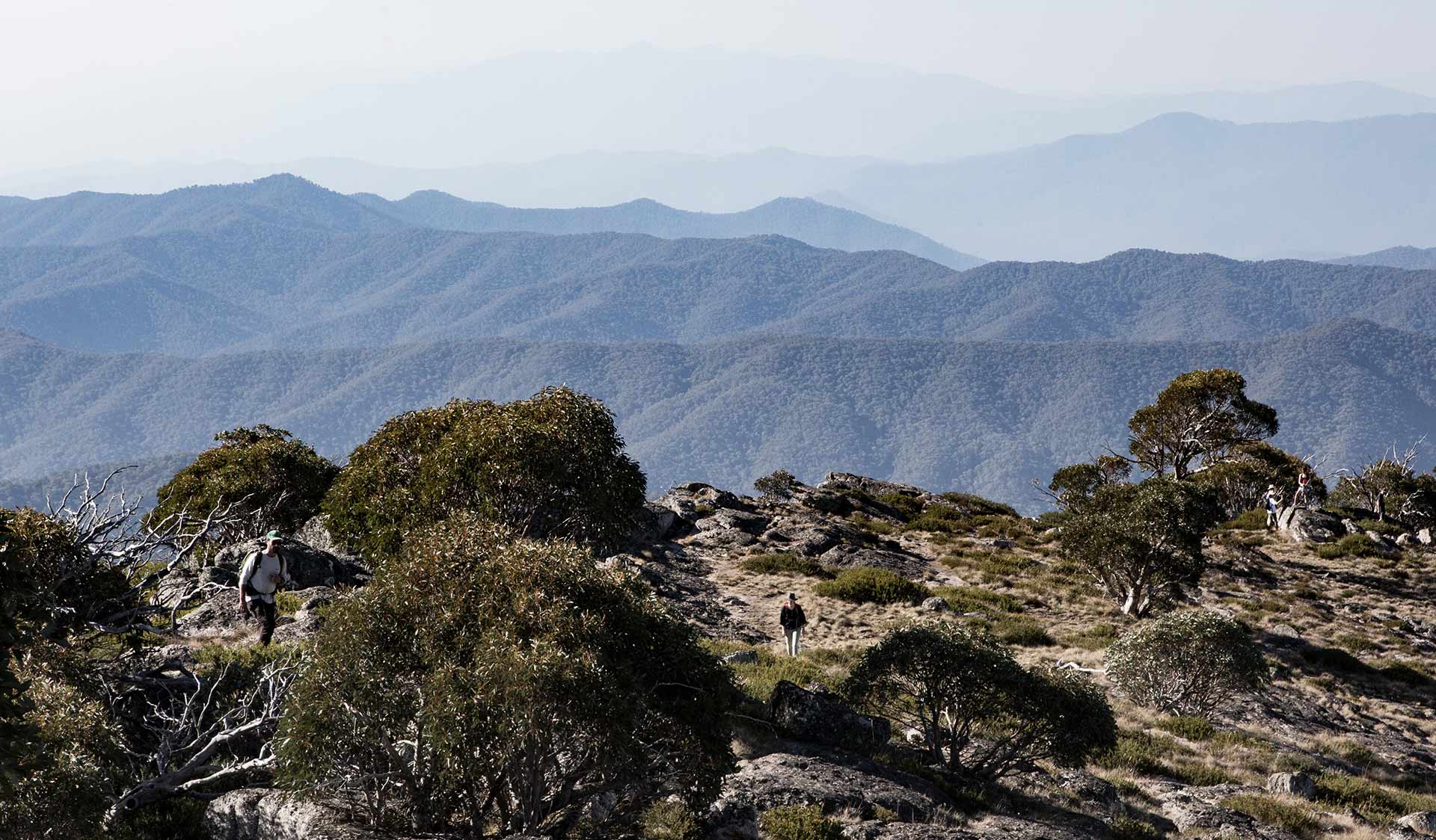 A woman hikes to the top of Mt Cobbler with spectacular views of the High Country in the background.