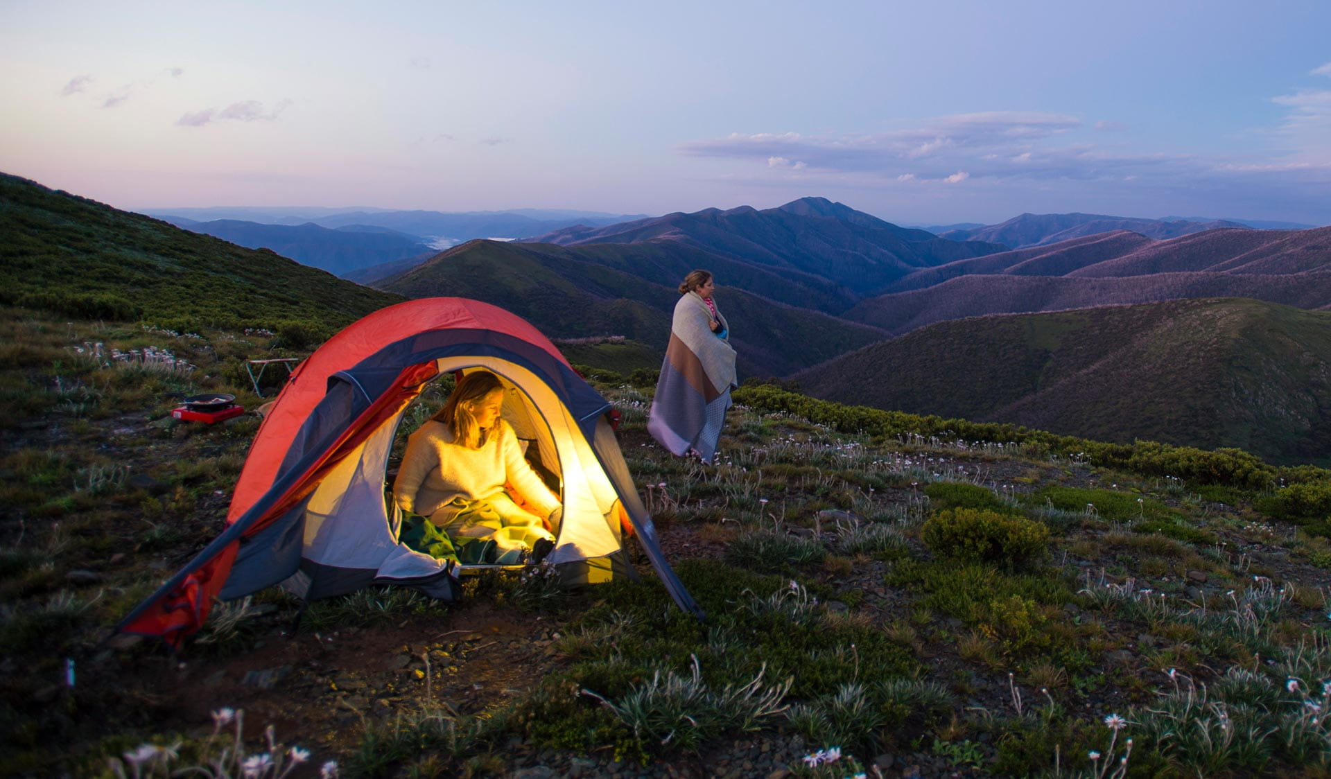 Two women camp in the Alpine National Park at twilight. 
