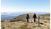 Two women walk towards the summit of Mt Bogong in the Alpine National Park.