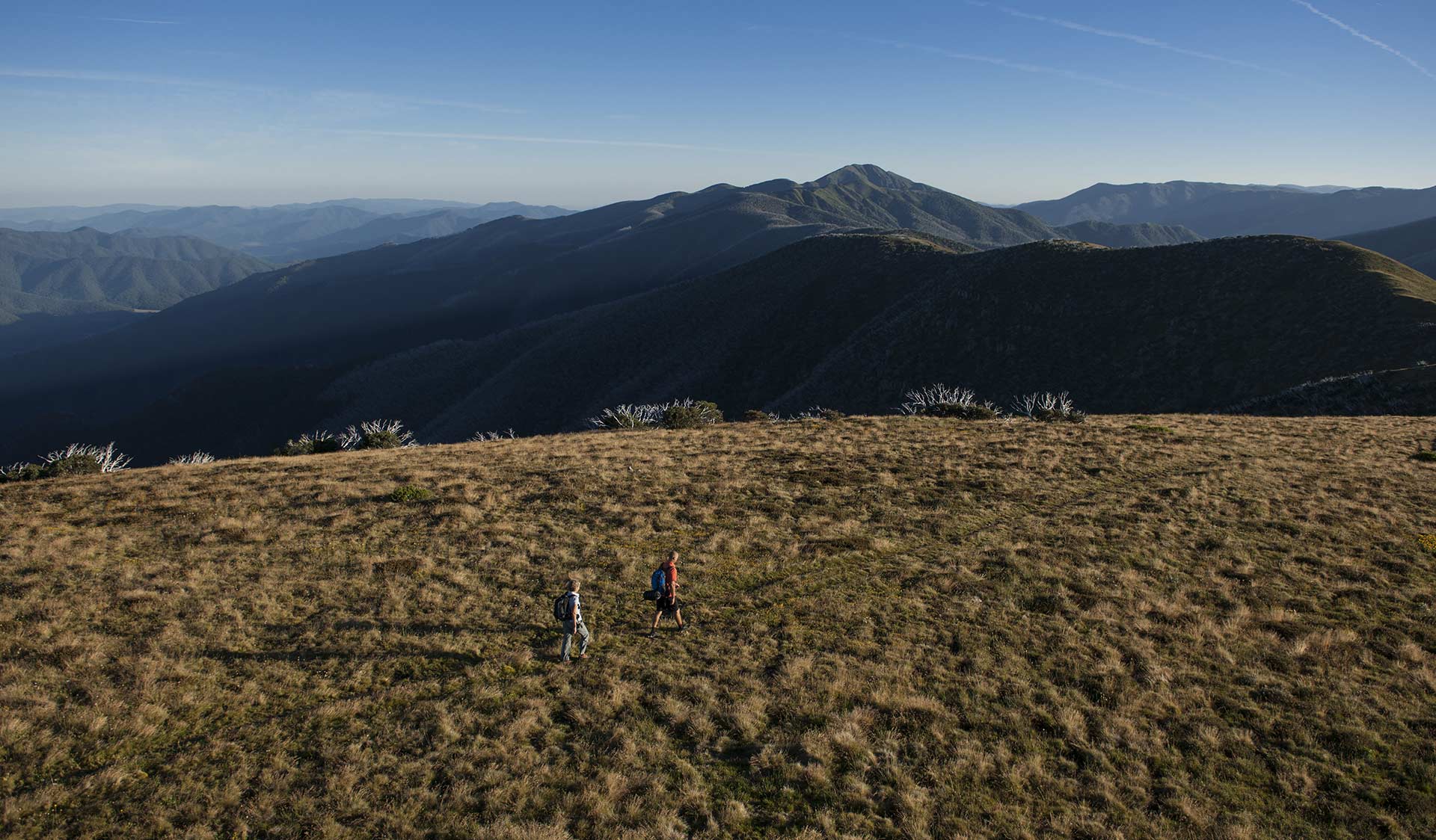 Two people walk along the Razorback towards Mt Feathertop in the Alpine National Park. 