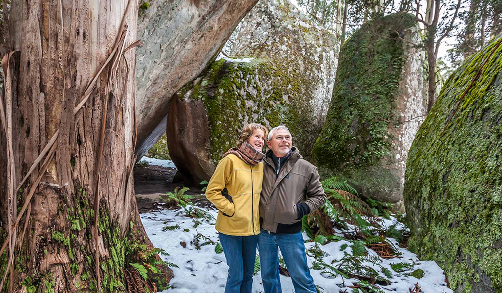 A middle aged couple walk through Mushroom Rocks on a cold winters day with snow on the ground.