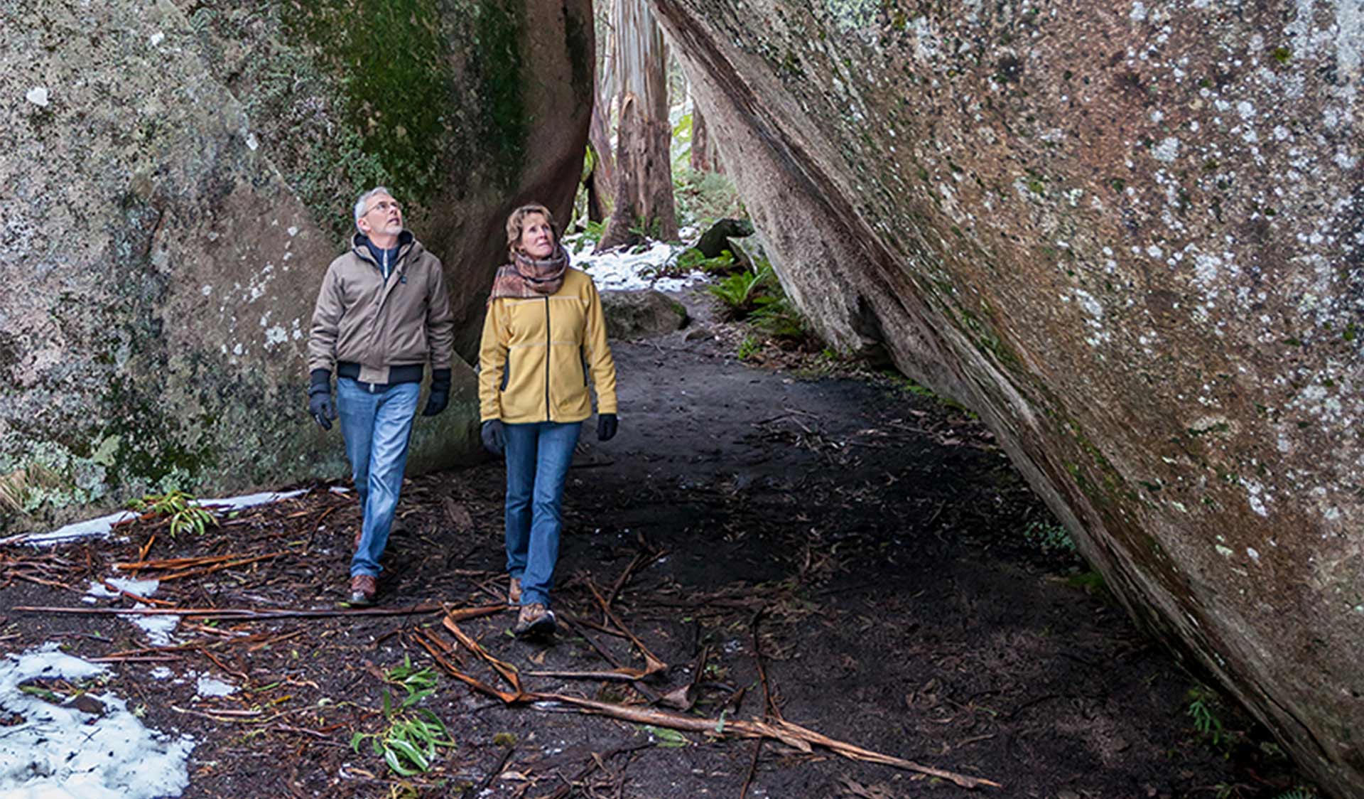 A middle aged couple walk through Mushroom Rocks on a cold winters day with snow on the ground.