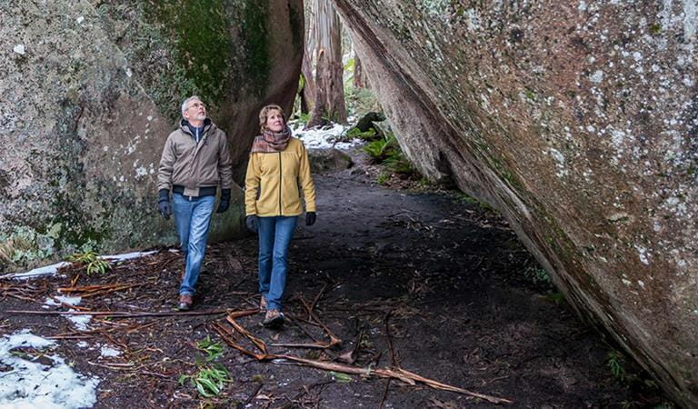 A middle aged couple walk through Mushroom Rocks on a cold winters day with snow on the ground.