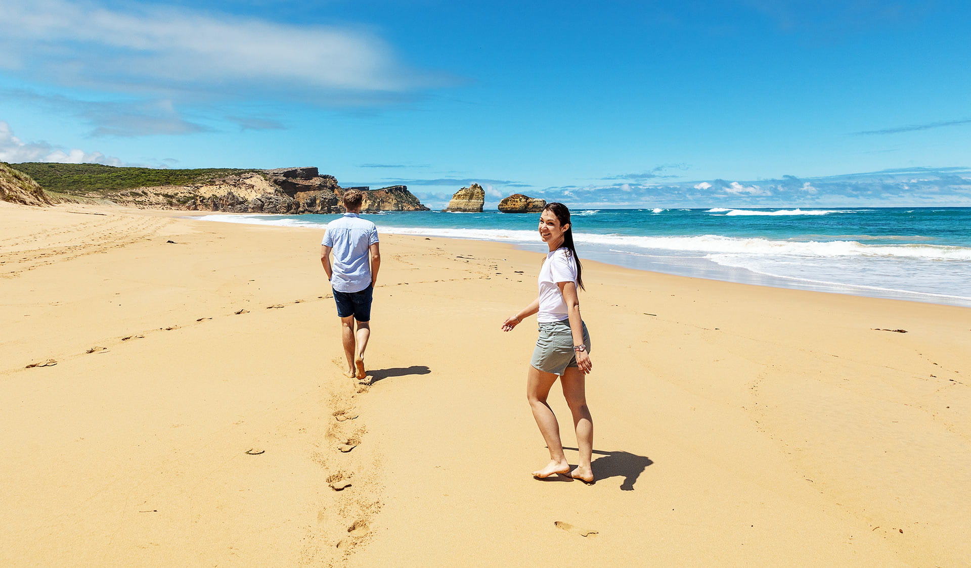 A couple walk along a beach at the Bay Islands