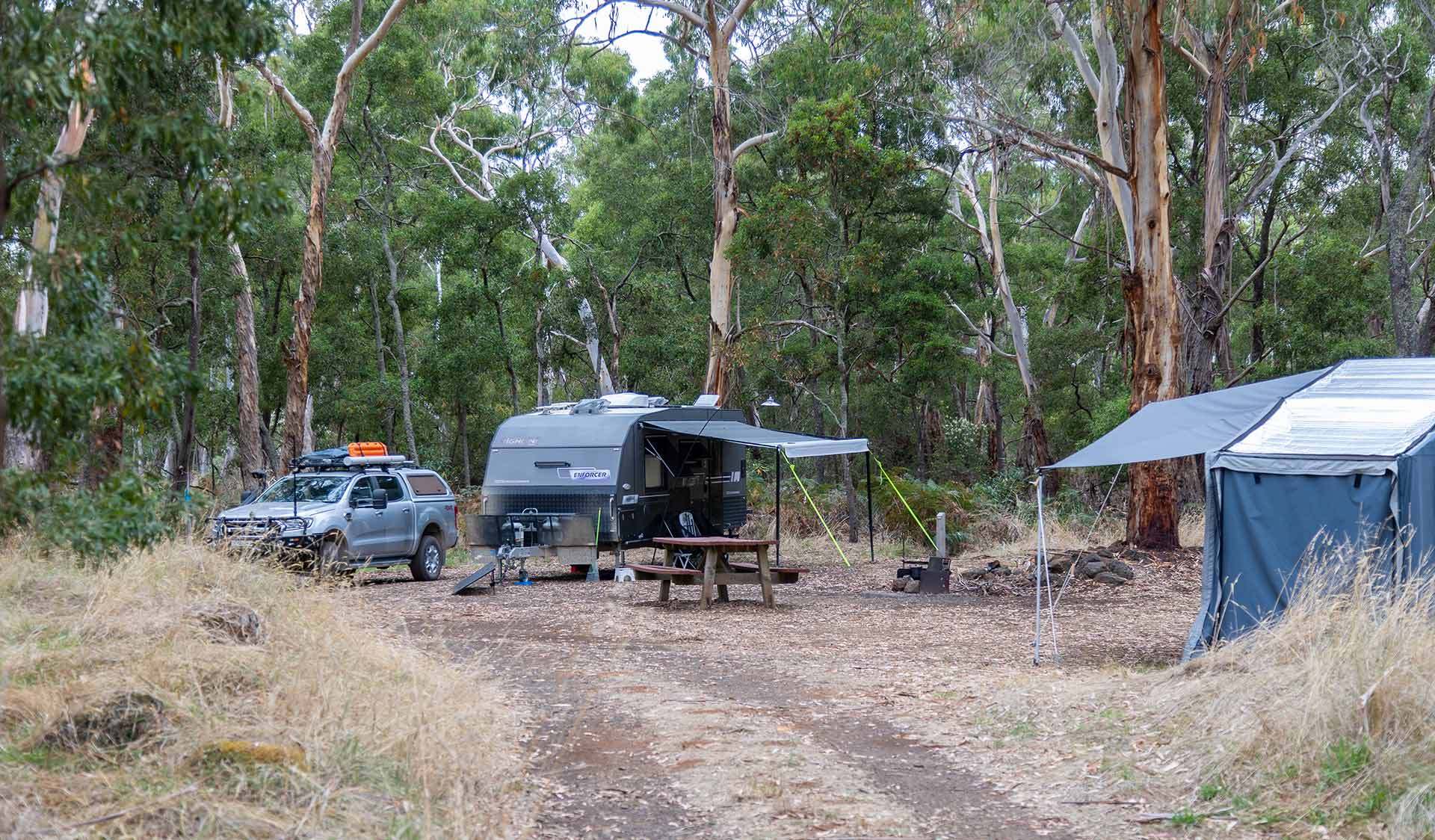 A vehicle path leads to caravan next to a picnic table at Budj Bim Campground at Budj Bim National Park