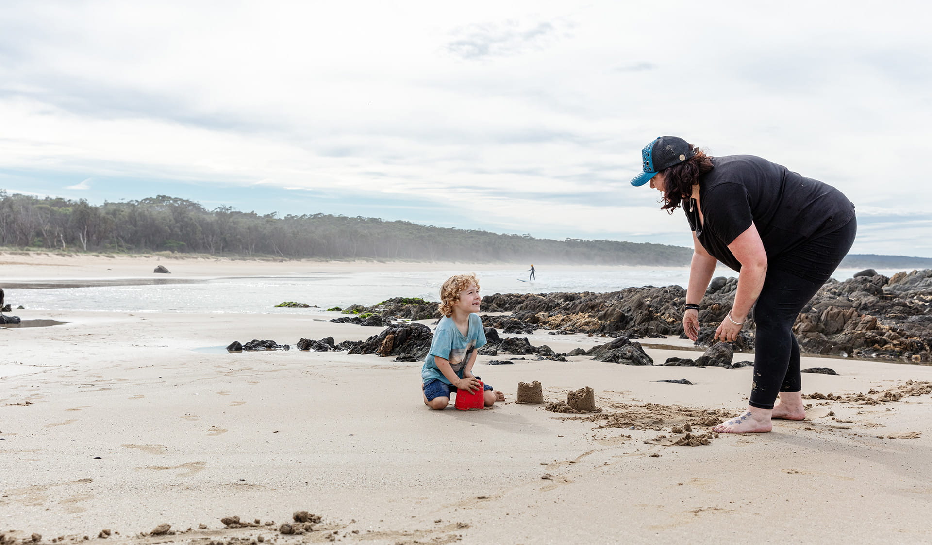 A woman and child play in the sand.