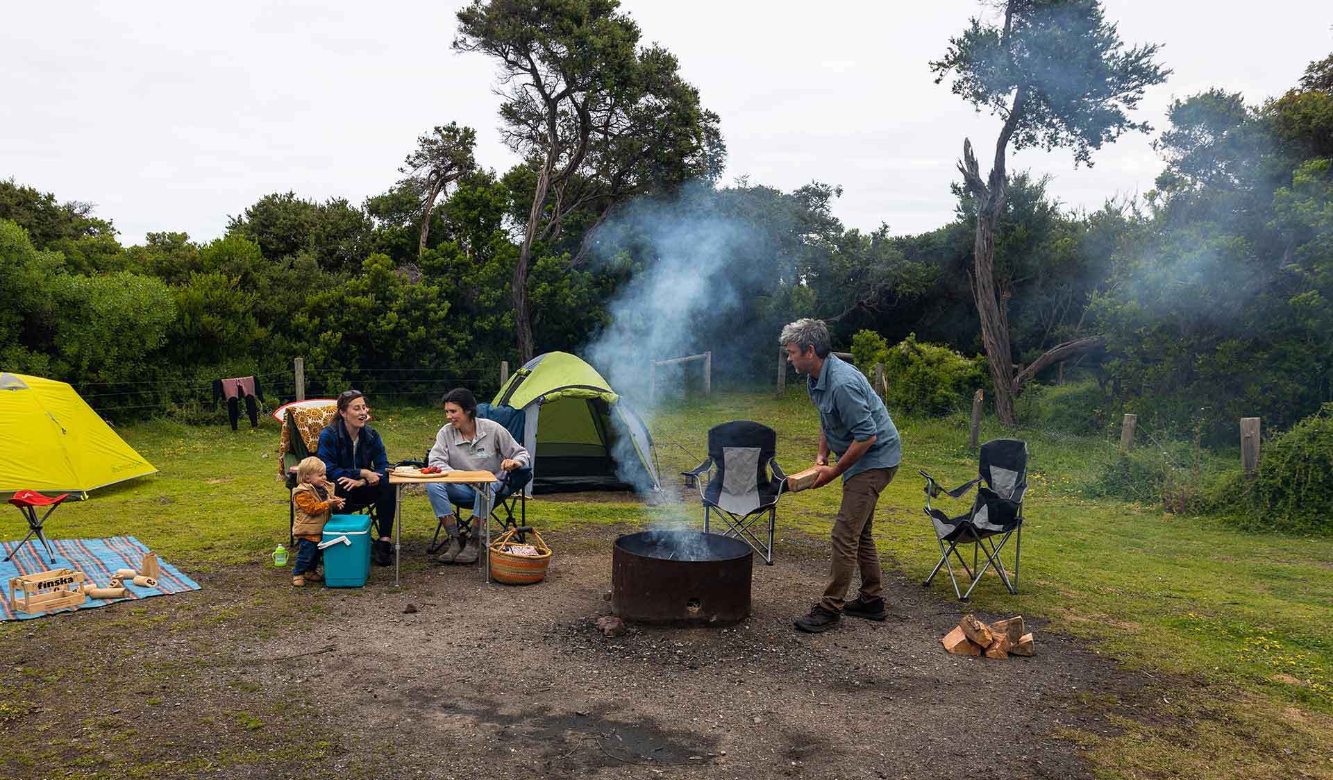 One man adds a log on to the fire at Bear Gully Campground at Cape Liptrap Coastal Park