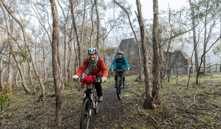 Two women mountain biking near the Garfields Water Wheel in Castlemaine Diggings National Heritage Park