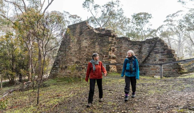 Two women walk in front the Garfield Water Wheel near Castlemaine.