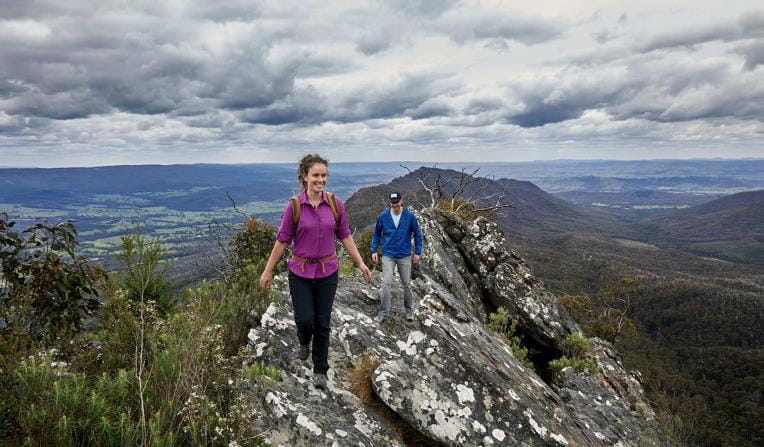 A woman leads her partner across the Razorback track surrounded by stunning views of the Rubicon Valley.