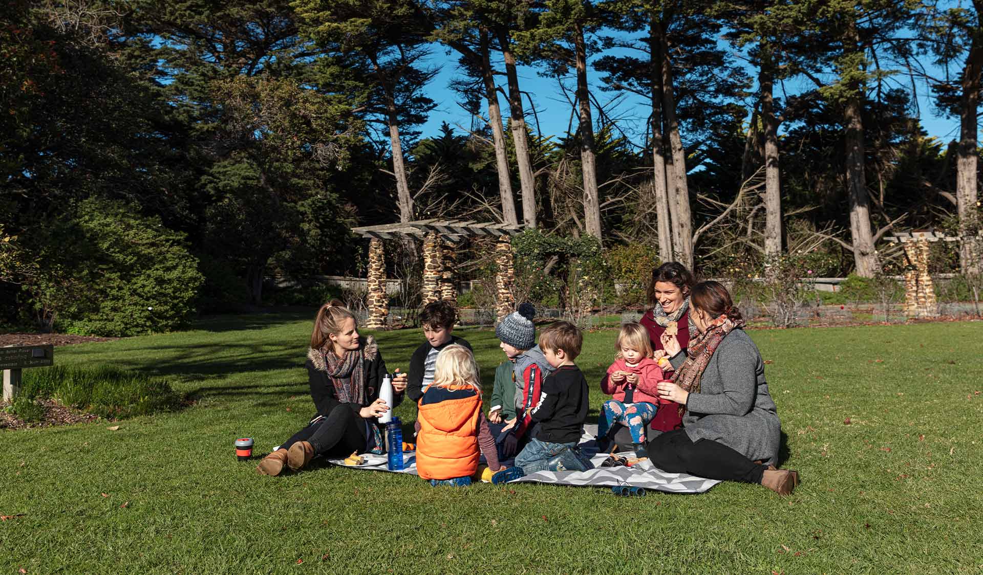 A group of families picnic on the lawn in front of Coolart Homestead