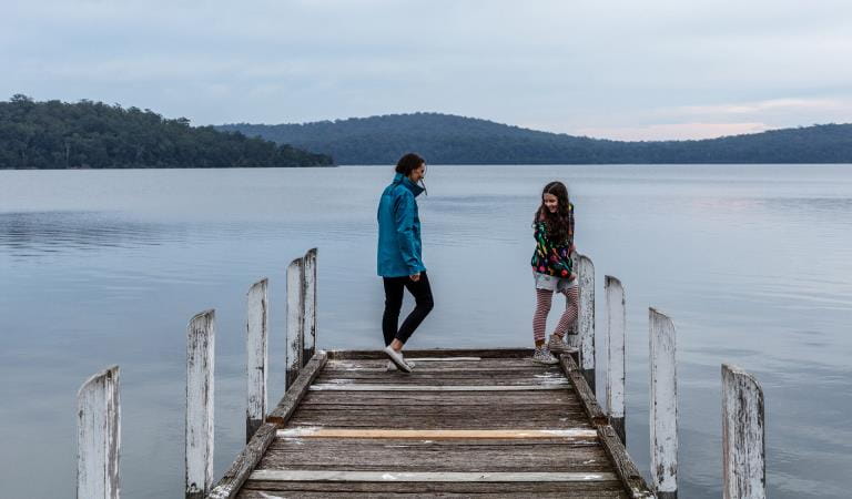 A mother and daughter linger at the end of a pier on the Mallacoota Inlet