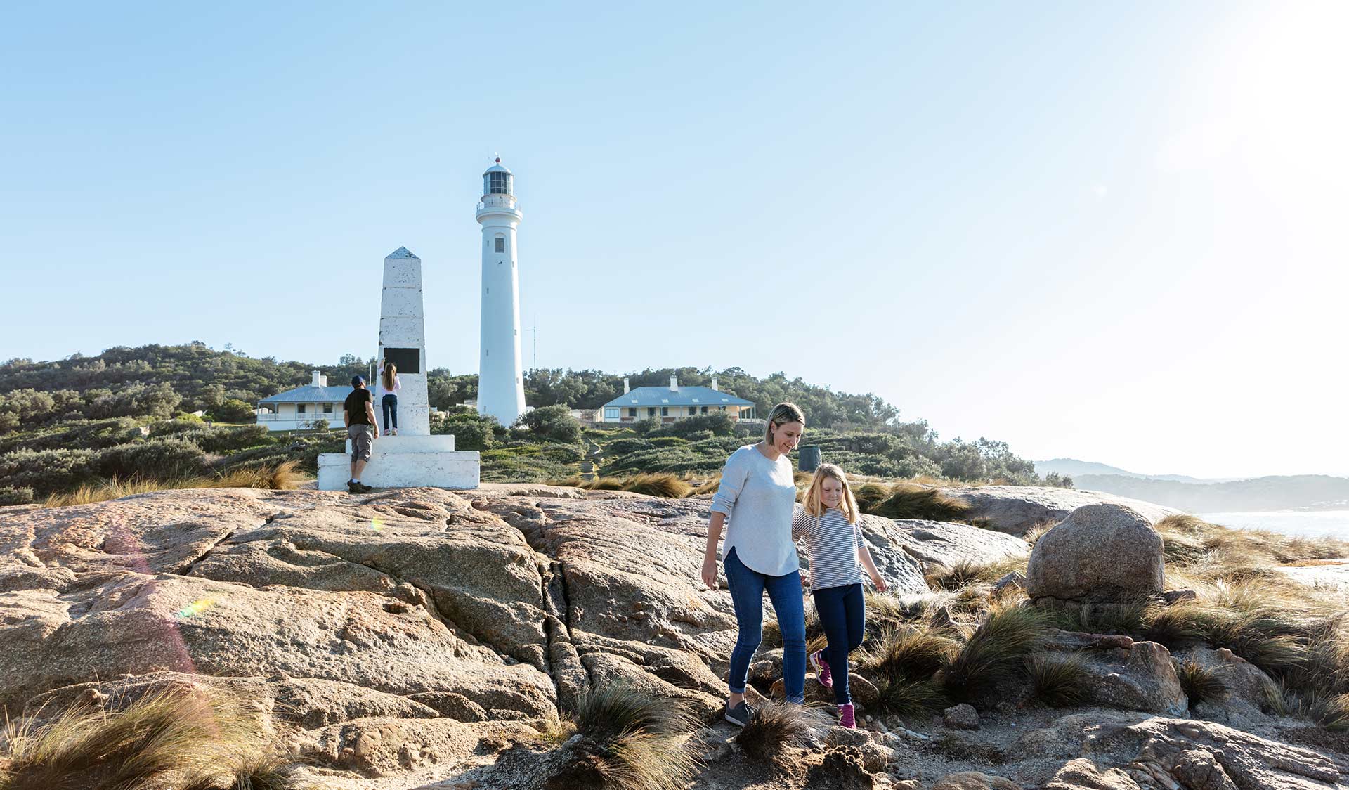A mother and daughter in front of the Point Hicks Lighthouse and cottages.