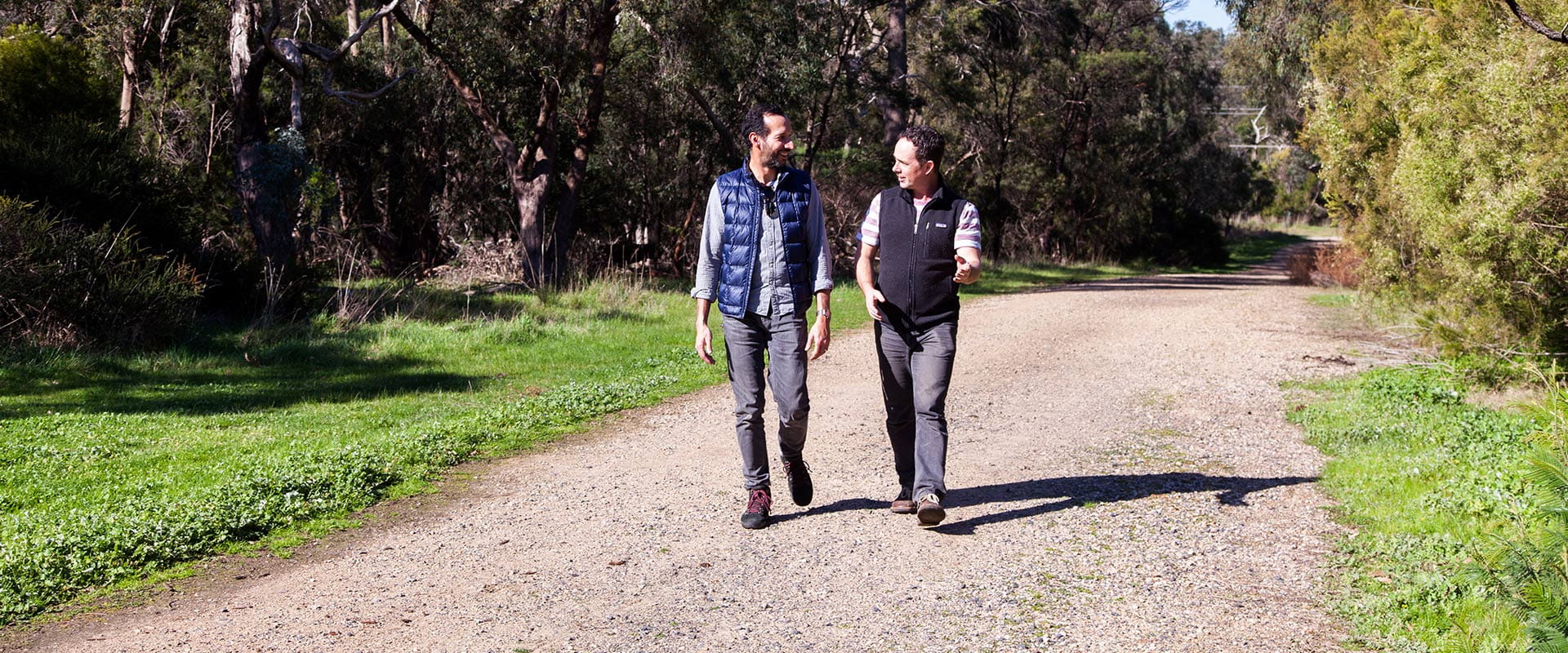 Two people are invested in conversation as they walk along a gravel path