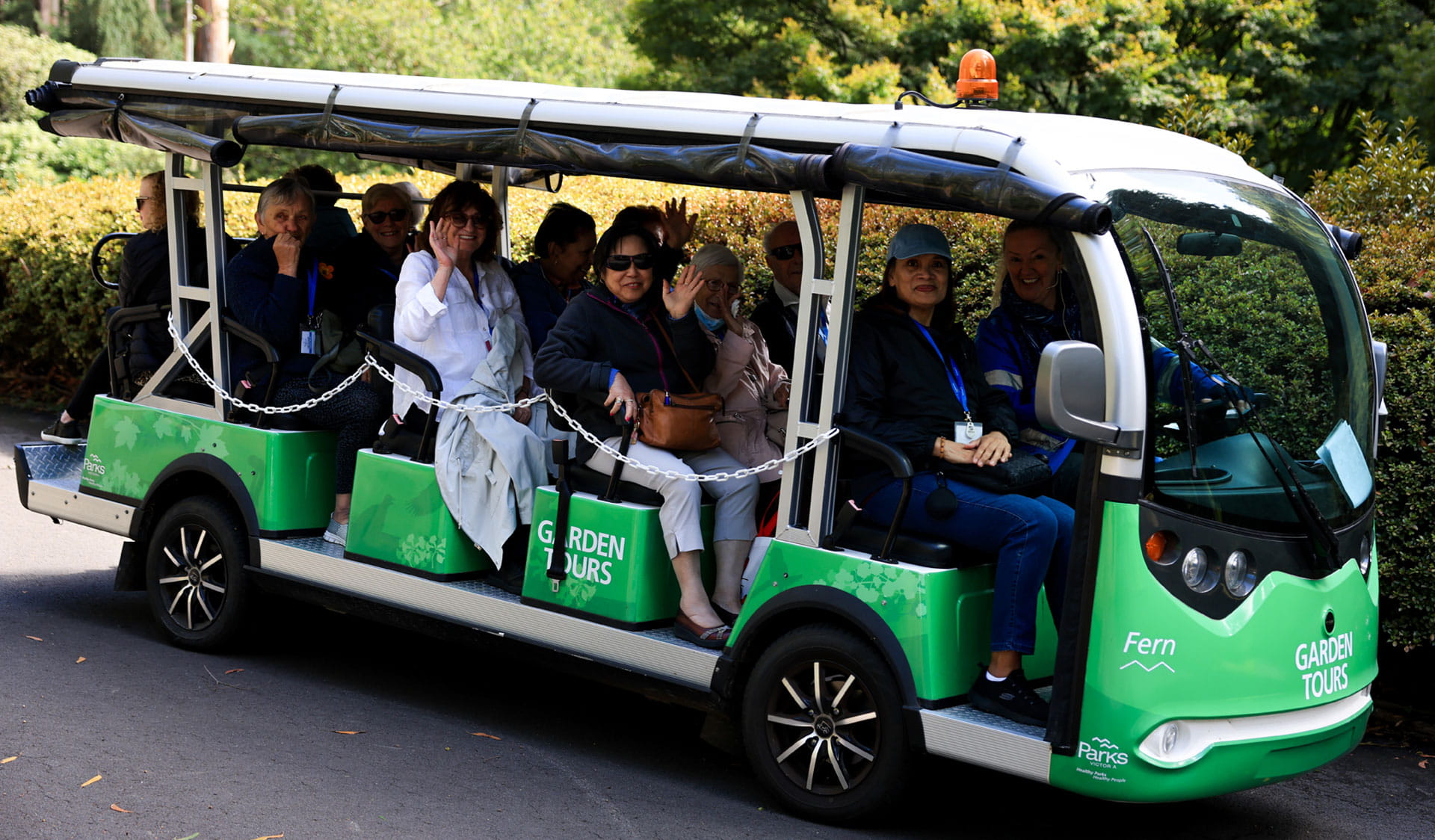 Visitors sitting and waving on the garden tours bus.