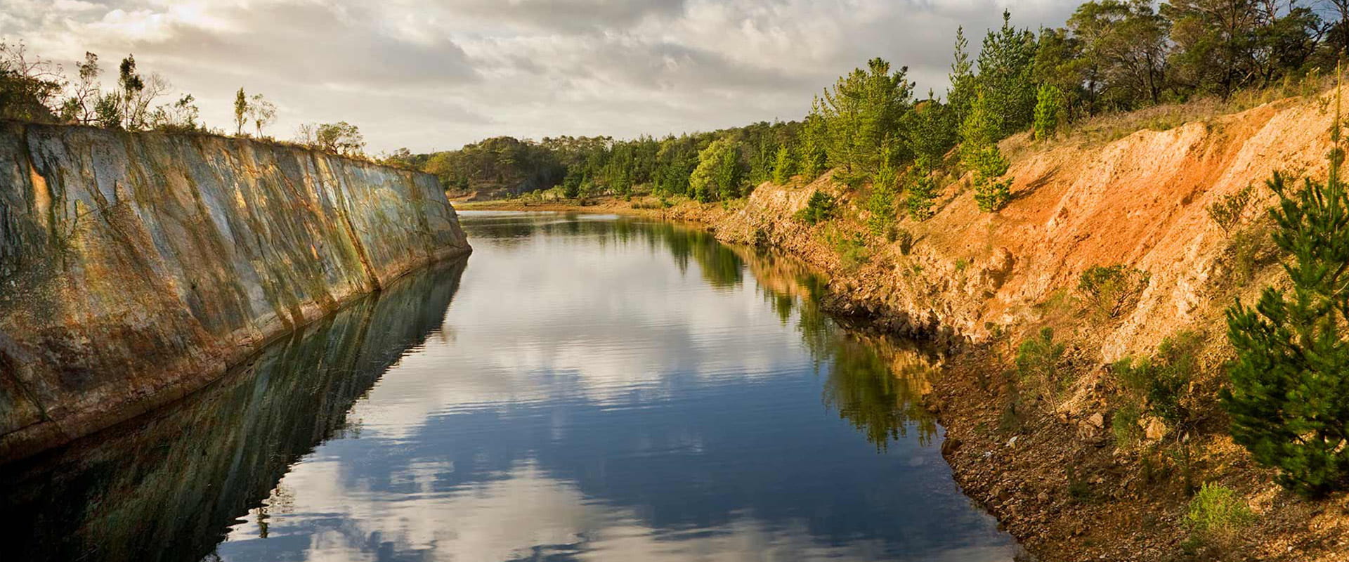 A wide river winds through the landscape surrounded by rocky walls and rugged bushland.