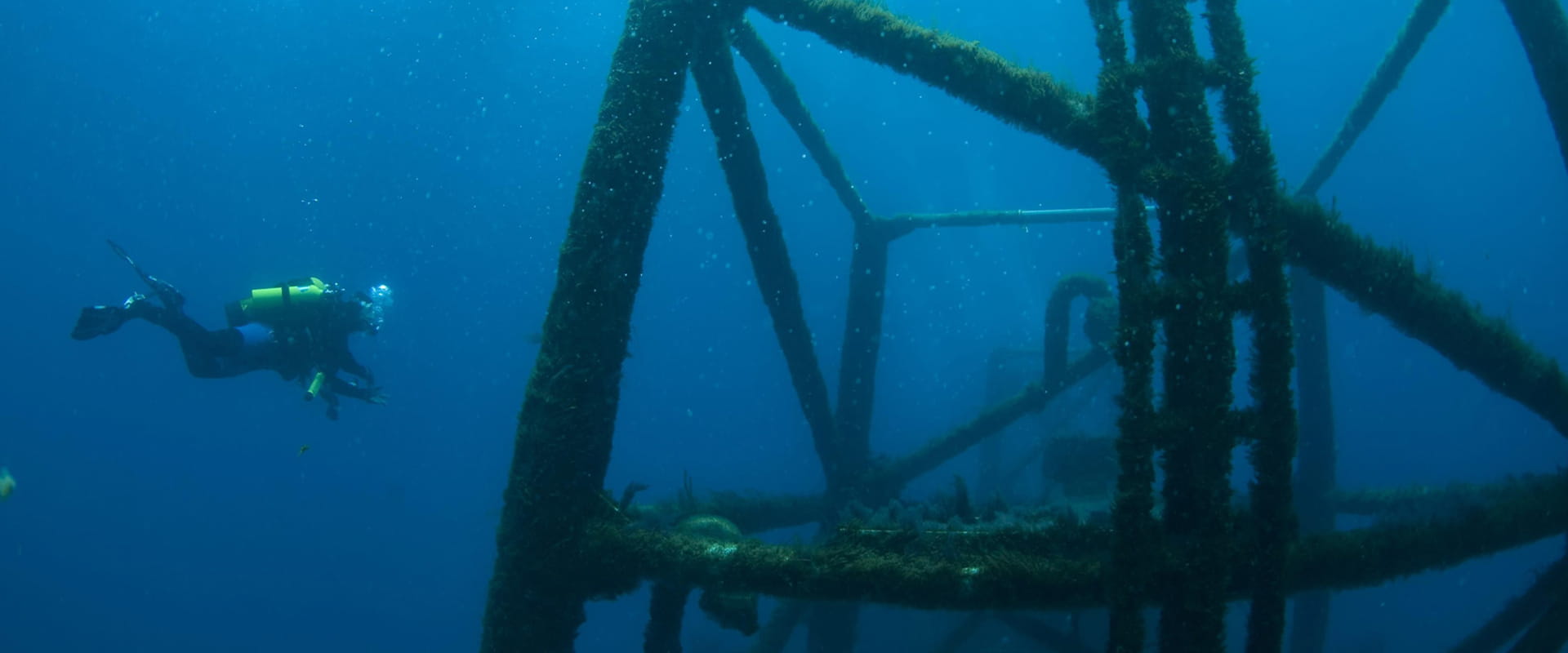 A scuba diver is underwater swimming towards part of the wreck.