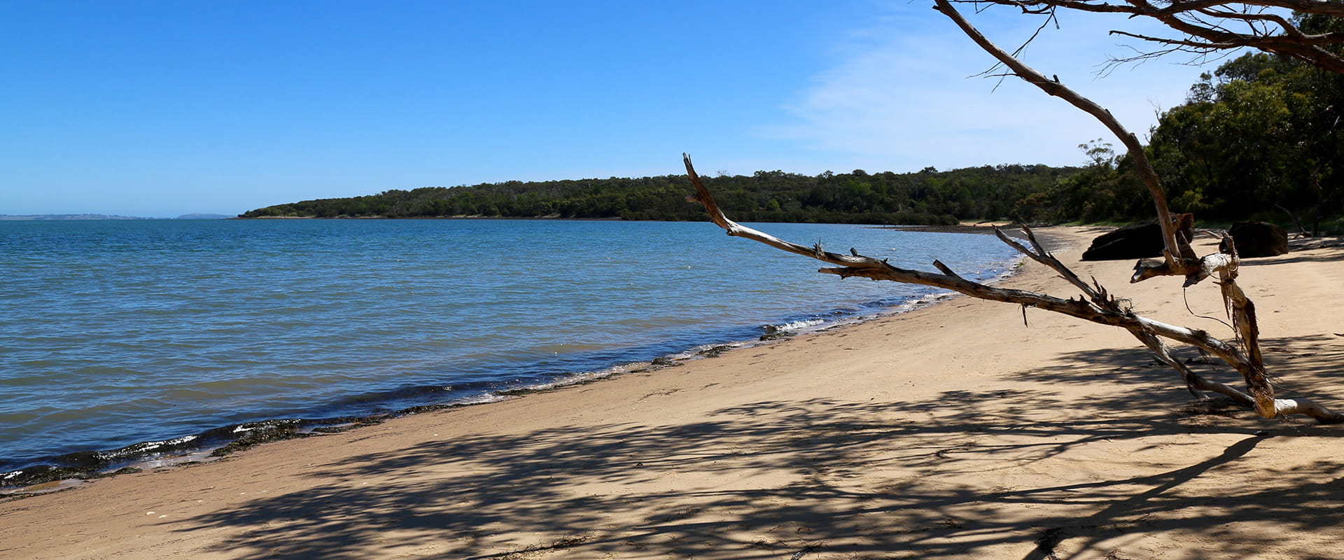 A beach without people that leads towards a coastal point