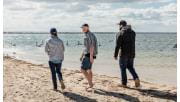 Three friends walk along the waters edge near Sperm Whale Head