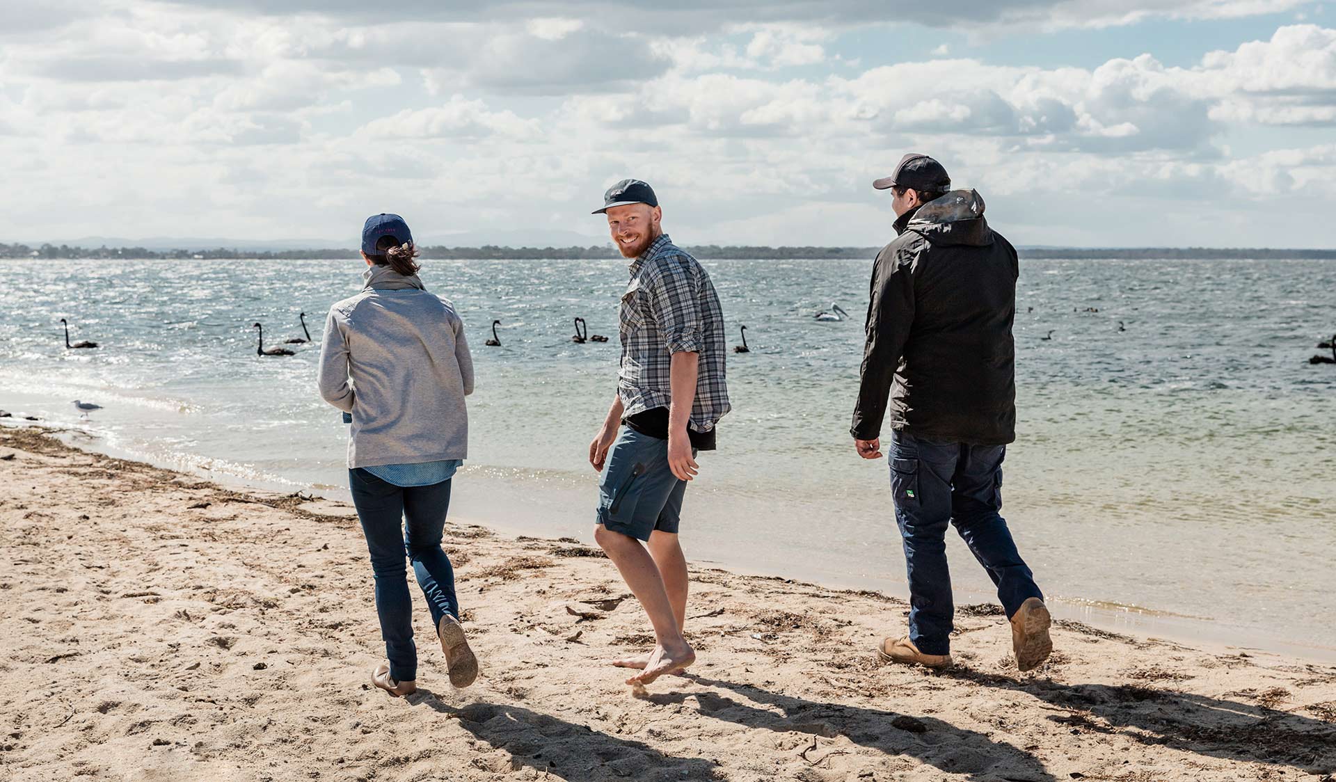 Three friends walk along the waters edge near Sperm Whale Head
