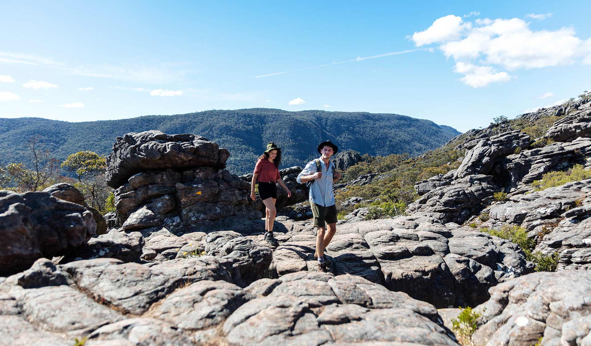 A young couple walks up through ancient lava flows to Sundial Peak in the Central Grampians.