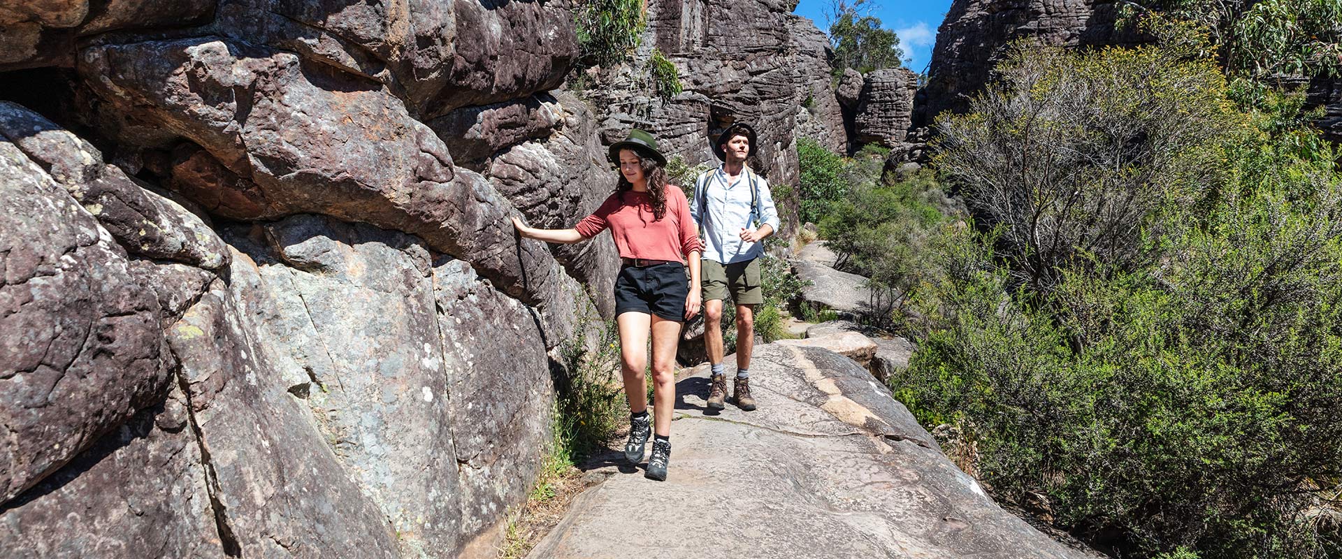 Two hikers walk along a rocky canyon