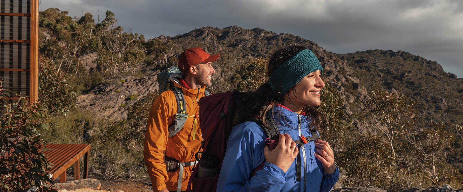 Two hikers stand by their hut and enjoy the sunset