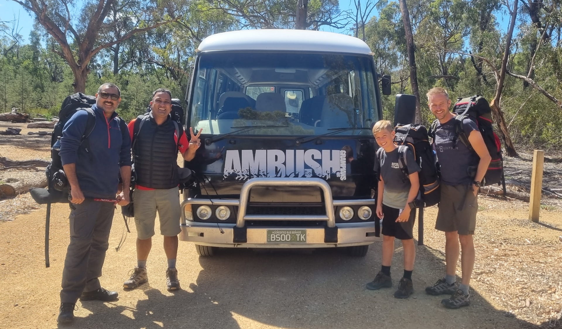 Visitors stand in front of a tour bus for Ambush Grampians