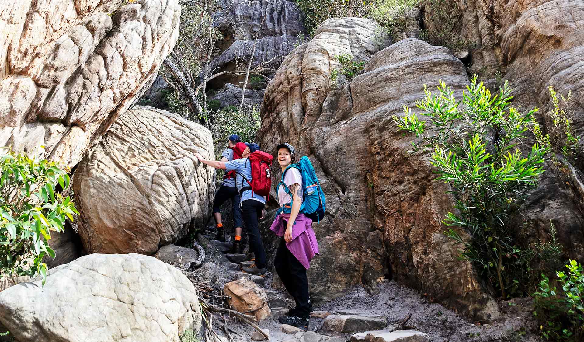 A group of three friends walk through the rocky ravines of the Northern Grampians.